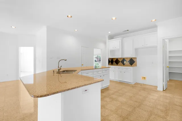 a view of an empty room with a window and kitchen view