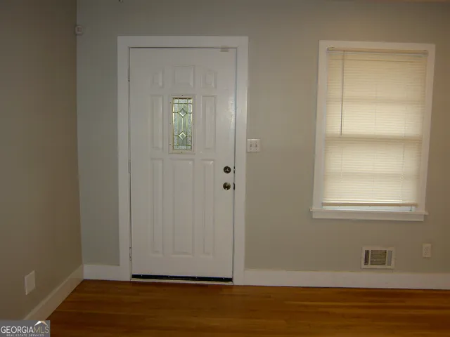 a view of an empty room with wooden floor and a window