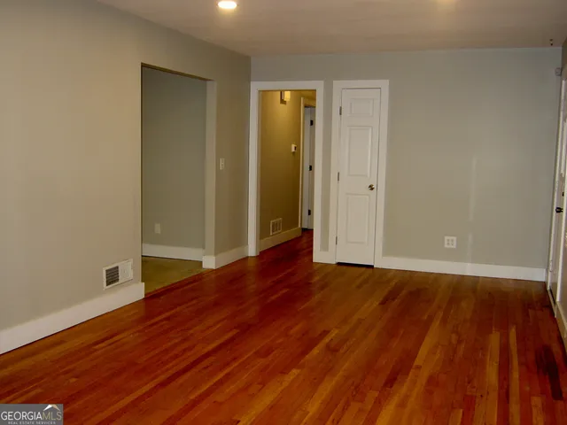 a view of an empty room with wooden floor and closet
