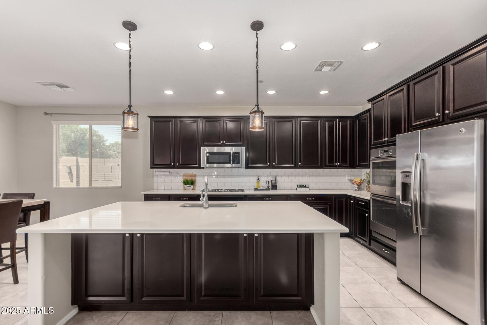 21243 West Coronado Road Buckeye, AZ 85396 - Photo 10 of 49 a kitchen with kitchen island stainless steel appliances a sink a stove a microwave a center island and chairs