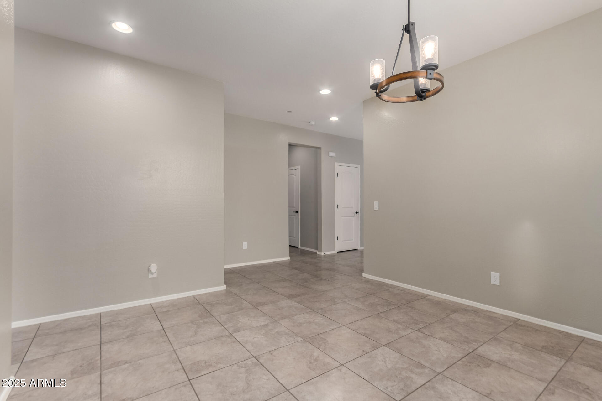 21243 West Coronado Road Buckeye, AZ 85396 - Photo 6 of 49 an empty room with a chandelier fan and kitchen view