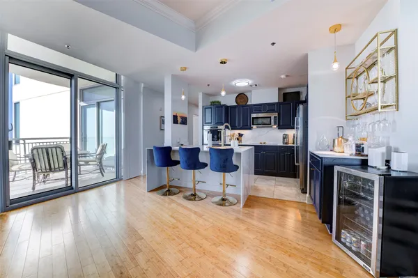 a living room with stainless steel appliances kitchen island granite countertop a table chairs and a view of kitchen