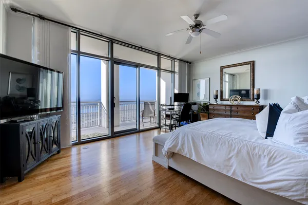 a spacious bedroom with a balcony a bed and a chandelier