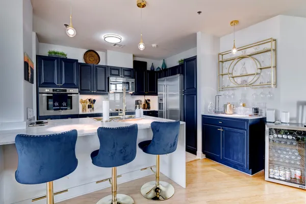 a kitchen with stainless steel appliances granite countertop a refrigerator a stove a sink and a dining table with wooden floor