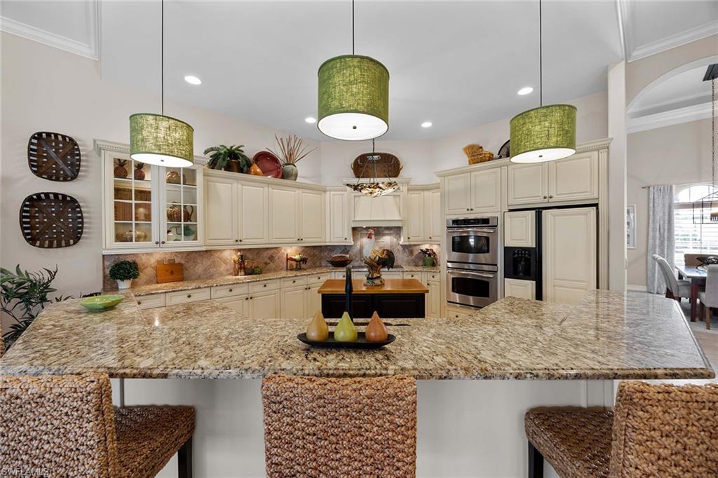 9038 Shenendoah Circle Naples, FL 34113 - Photo 11 of 50 a kitchen with a sink a stove and chairs