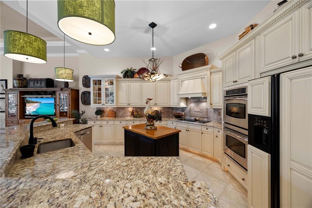 9038 Shenendoah Circle Naples, FL 34113 - Photo 12 of 50 a kitchen with stainless steel appliances kitchen island granite countertop a stove and white cabinets