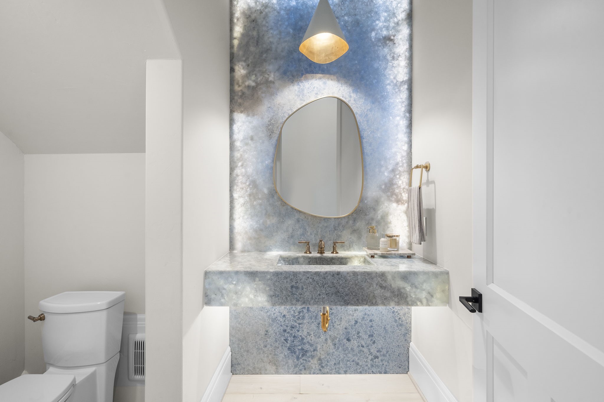 5511 Fulbrook Road Fulshear, TX 77441 - Photo 28 of 50 The guest bathroom features a gorgeous Onyx focal wall with back lighting highlighting how truly stunning this piece is. This wall is complimented beautifully with gold plumbing fixtures.