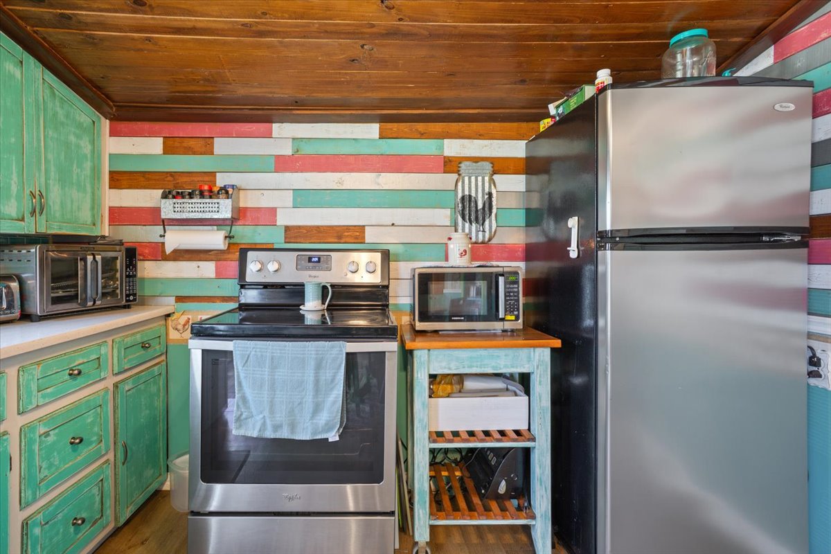 2804 Auction Barn Road Belton, TX 76513 - Photo 12 of 22 Kitchen featuring green cabinetry, stainless steel appliances, wood ceiling, light countertops, and dark wood-type flooring