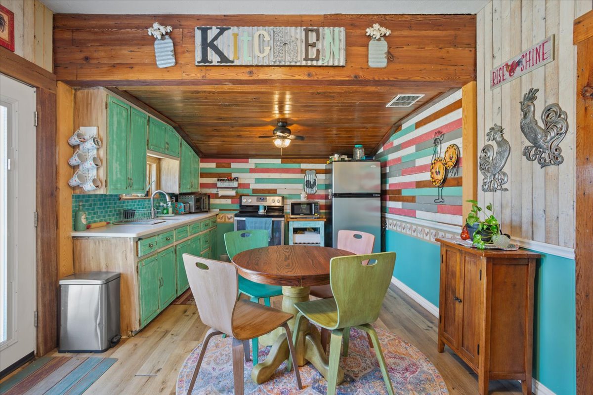 2804 Auction Barn Road Belton, TX 76513 - Photo 9 of 22 Kitchen with light countertops, wood walls, stainless steel appliances, green cabinets, and light wood finished floors