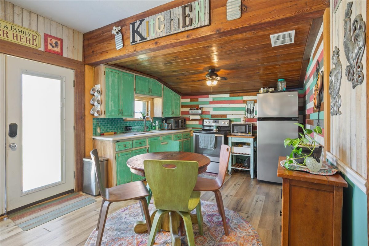 2804 Auction Barn Road Belton, TX 76513 - Photo 10 of 22 Kitchen featuring stainless steel appliances, light countertops, light wood finished floors, green cabinetry, and wooden walls
