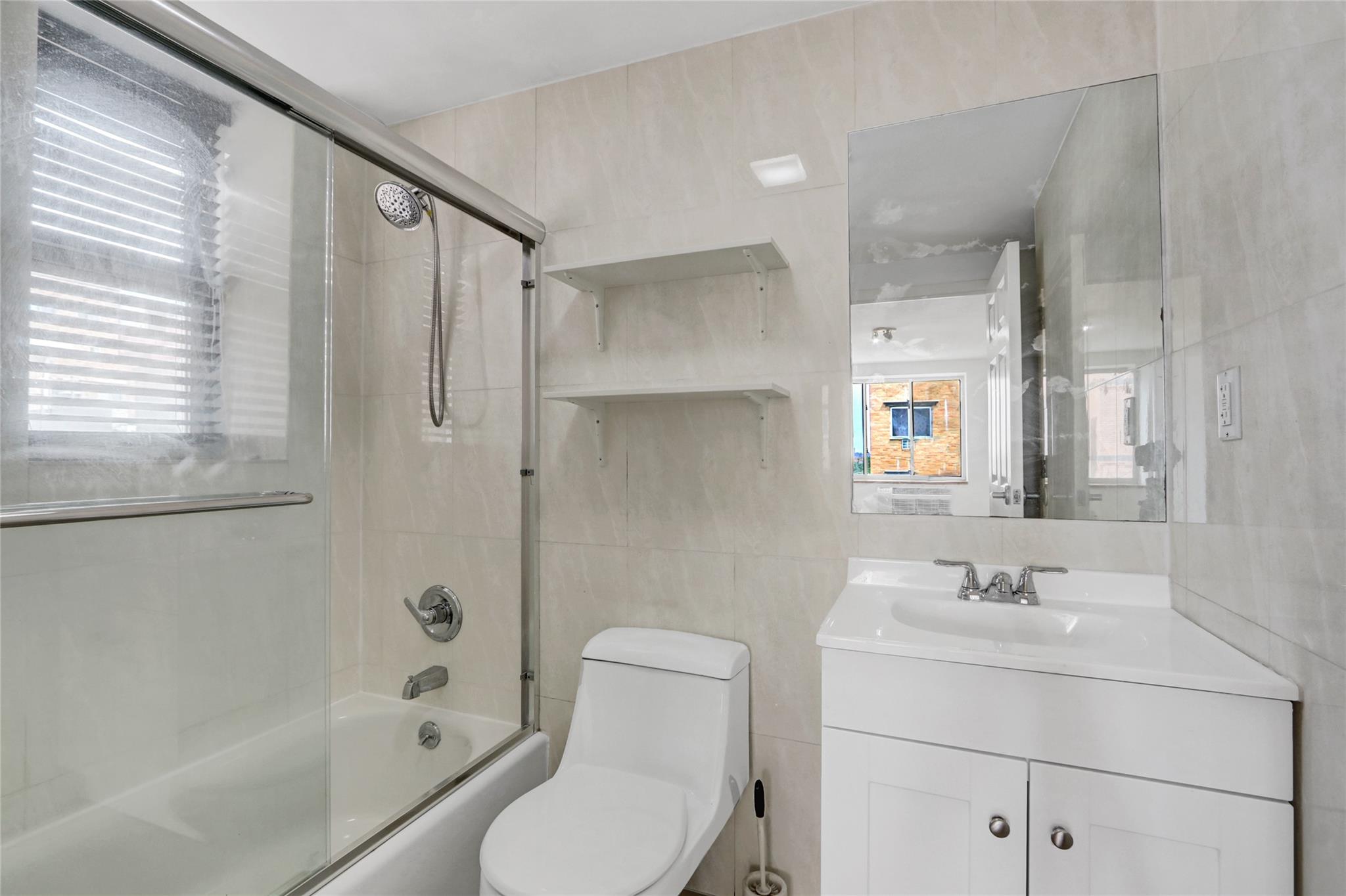 43-17 Union Street, Unit 5A Queens, NY 11355 - Photo 11 of 19 Full bath with tile walls, vanity, bath / shower combo with glass door, and healthy amount of natural light