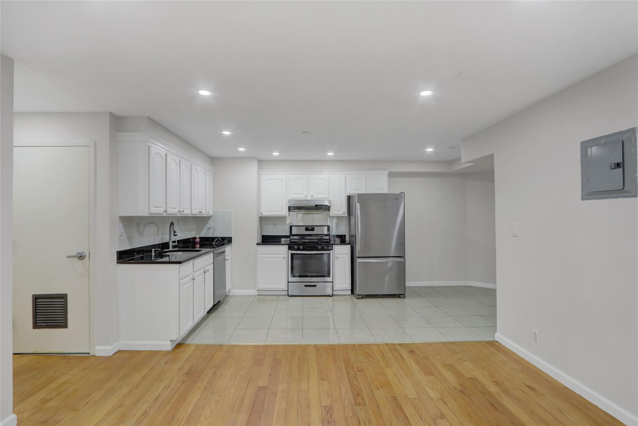 43-17 Union Street, Unit 5A Queens, NY 11355 - Photo 8 of 19 Kitchen with stainless steel appliances, light wood-type flooring, dark countertops, electric panel, and white cabinetry