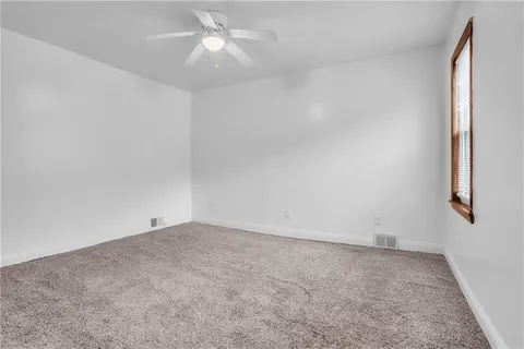 an empty room with fan and windows