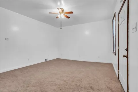 an empty room with a window and ceiling fan