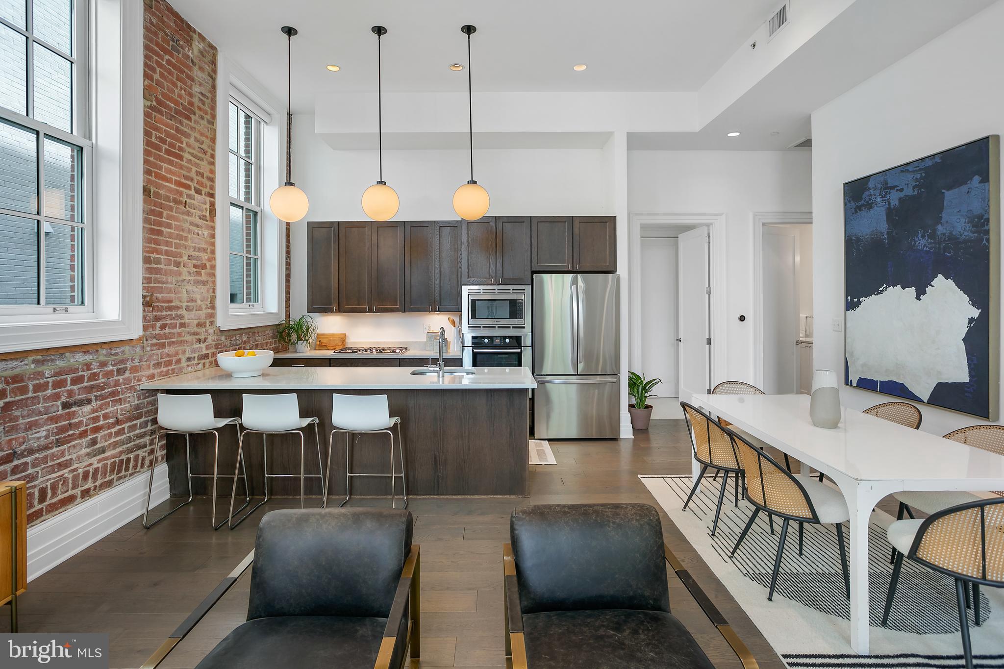 901 D Street Northeast, Unit 102 Washington, DC 20002 - Photo 10 of 40 a open kitchen with stainless steel appliances kitchen island granite countertop a table chairs and a refrigerator