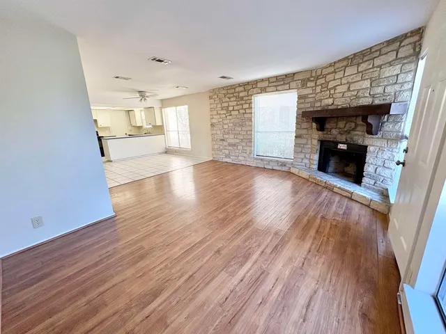 an empty room with wooden floor fireplace and windows