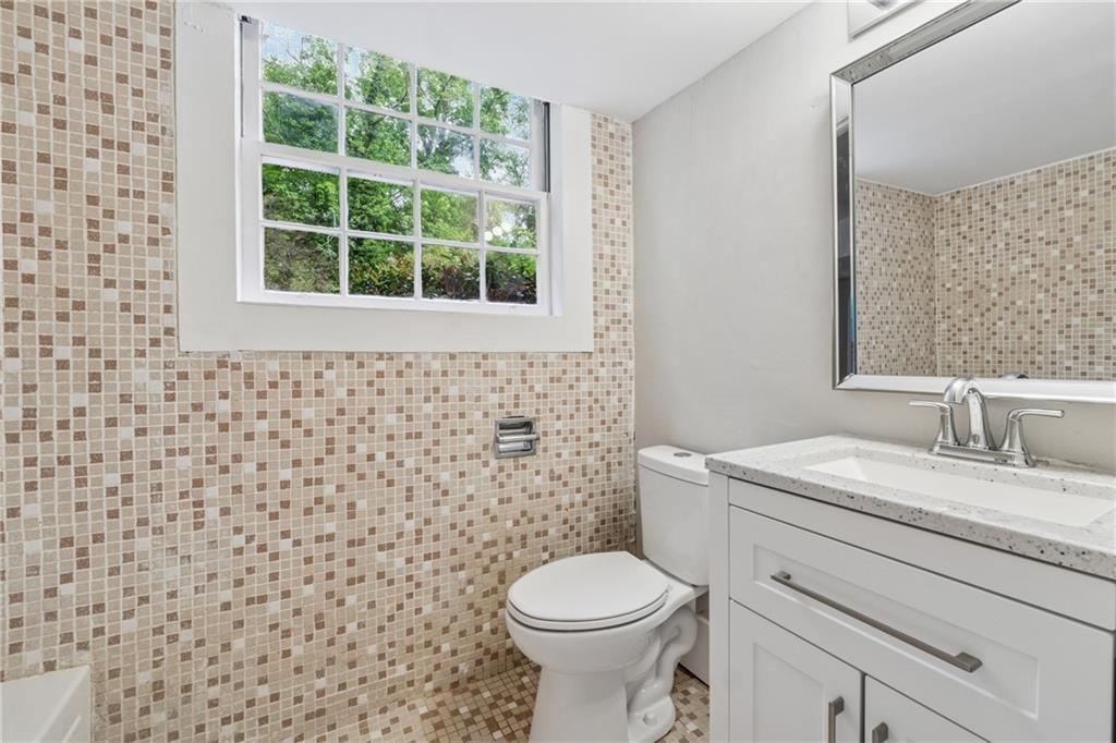 4616 Greensprings Road Atlanta, GA 30337 - Photo 19 of 26 a bathroom with a granite countertop toilet a sink and a window