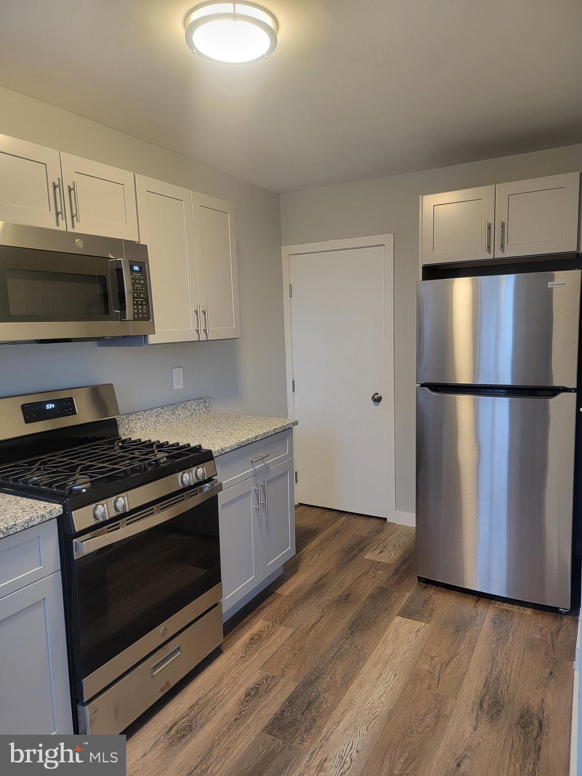 2896 Cushing Road Camden, NJ 08104 - Photo 6 of 31 a kitchen with granite countertop a stove a microwave a refrigerator a sink and cabinets