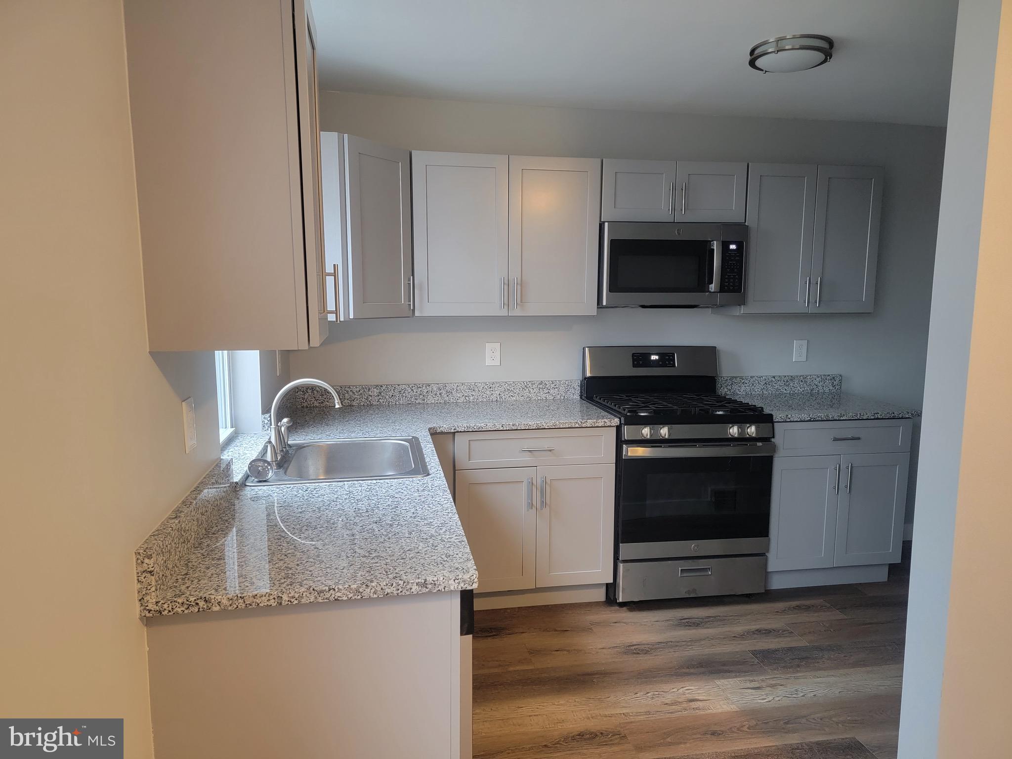2896 Cushing Road Camden, NJ 08104 - Photo 8 of 31 a kitchen with granite countertop a sink and a stove top oven with wooden floor
