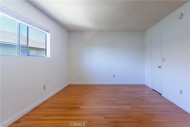 a view of an empty room with wooden floor and closet
