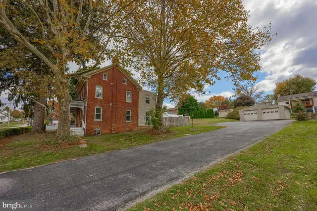 a brick building sitting in middle of a yard with large trees