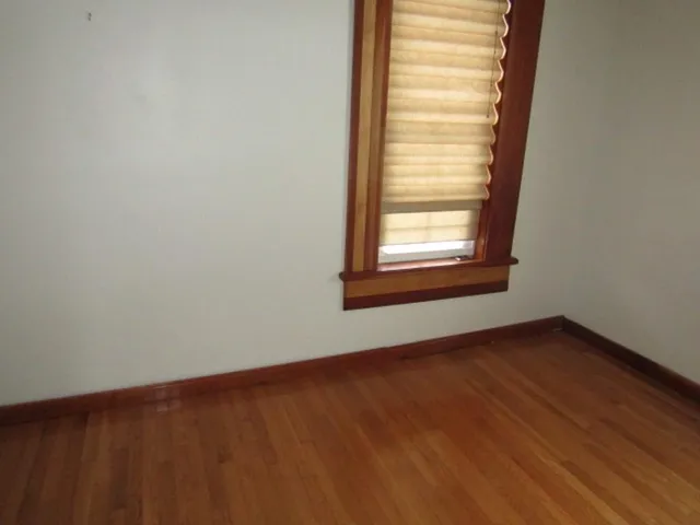 a view of an empty room with wooden floor and closet