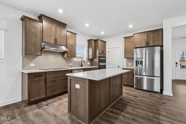 a kitchen with kitchen island granite countertop wooden cabinets and stainless steel appliances