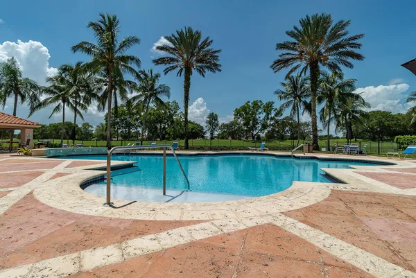 a view of a swimming pool with a yard and palm trees