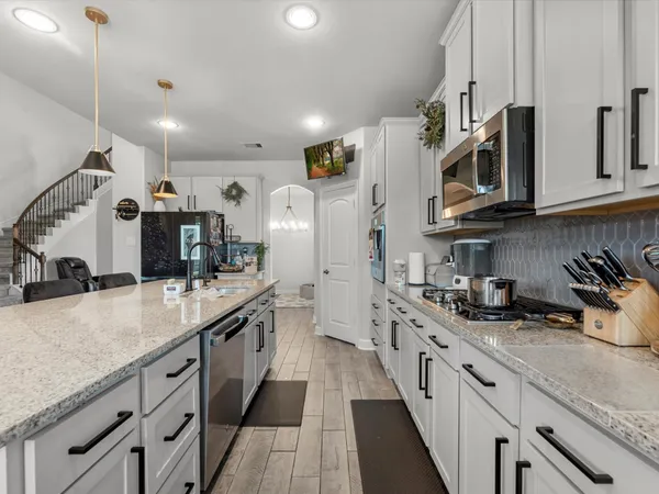 a large kitchen with stainless steel appliances granite countertop a lot of counter space and a sink