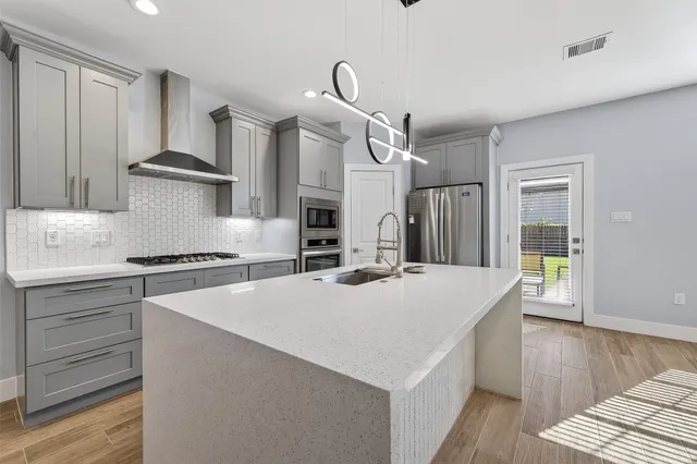 a kitchen with a stove a sink a refrigerator and wooden floor