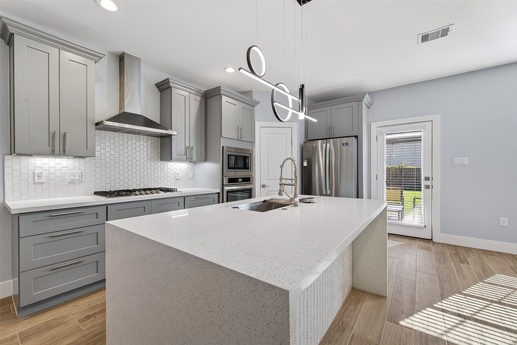 a kitchen with a stove a sink a refrigerator and wooden floor