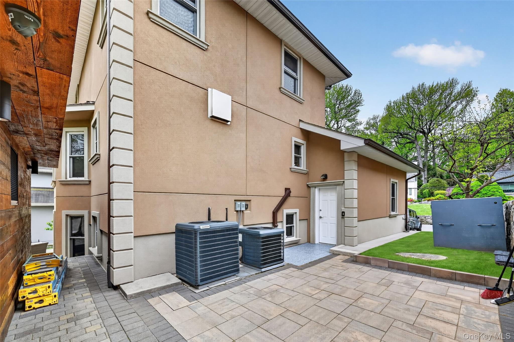 65 Wildway Bronxville, NY 10708 - Photo 17 of 42 Exterior featuring stucco finish, decorative trim, multiple windows, a white entry door, and a paved patio area
