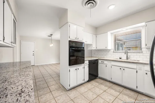 a kitchen with granite countertop a sink a counter space appliances and cabinets