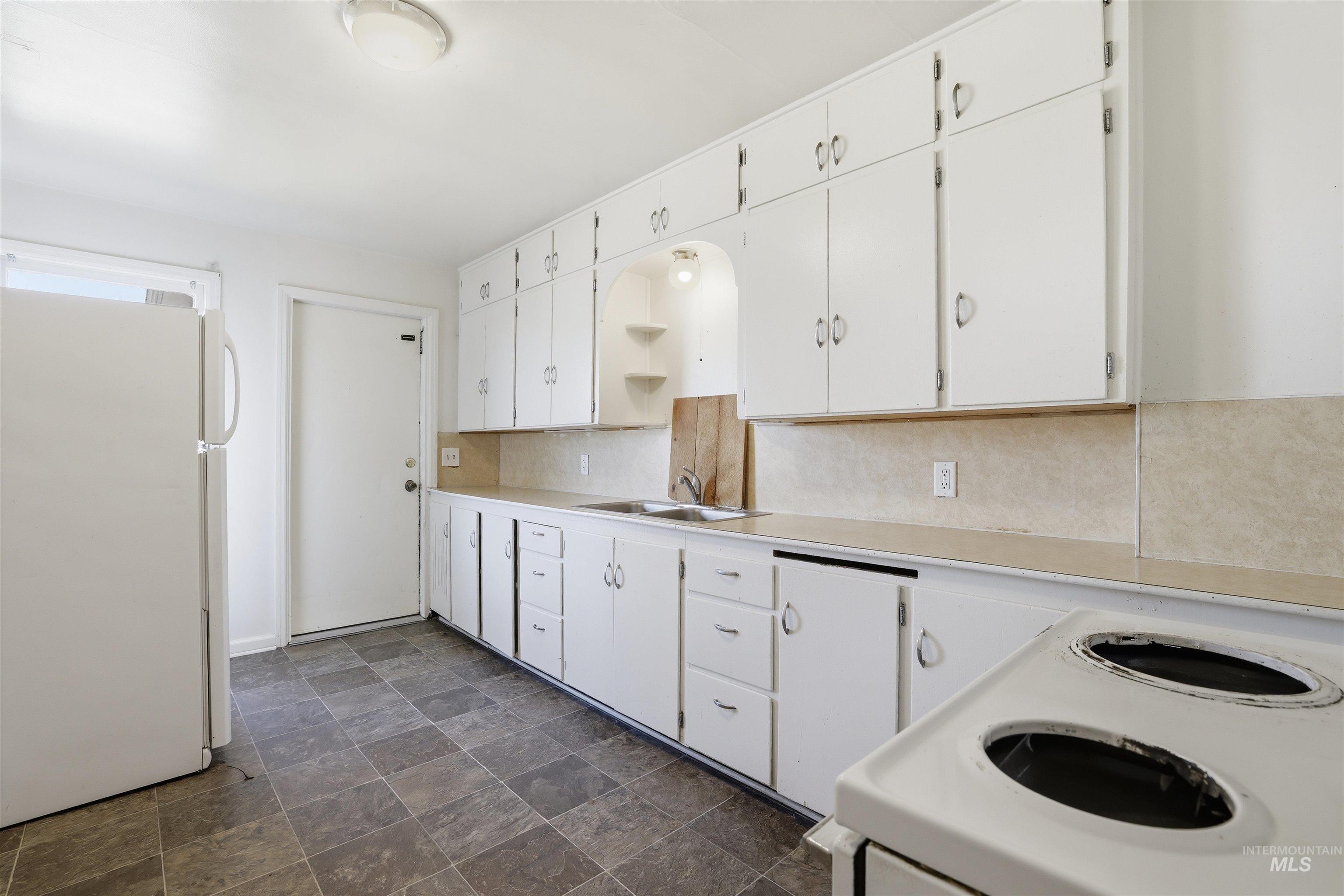 116 13th Avenue North Buhl, ID 83316 - Photo 12 of 37 Kitchen with white cabinetry, white appliances, stone finish floors, light countertops, and backsplash