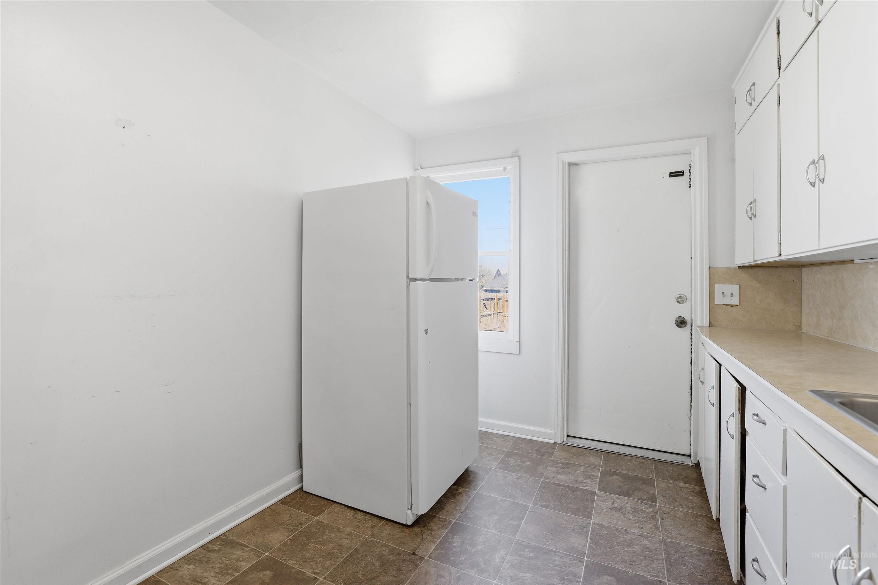 116 13th Avenue North Buhl, ID 83316 - Photo 15 of 37 Kitchen featuring white cabinetry, freestanding refrigerator, light countertops, and stone finish flooring