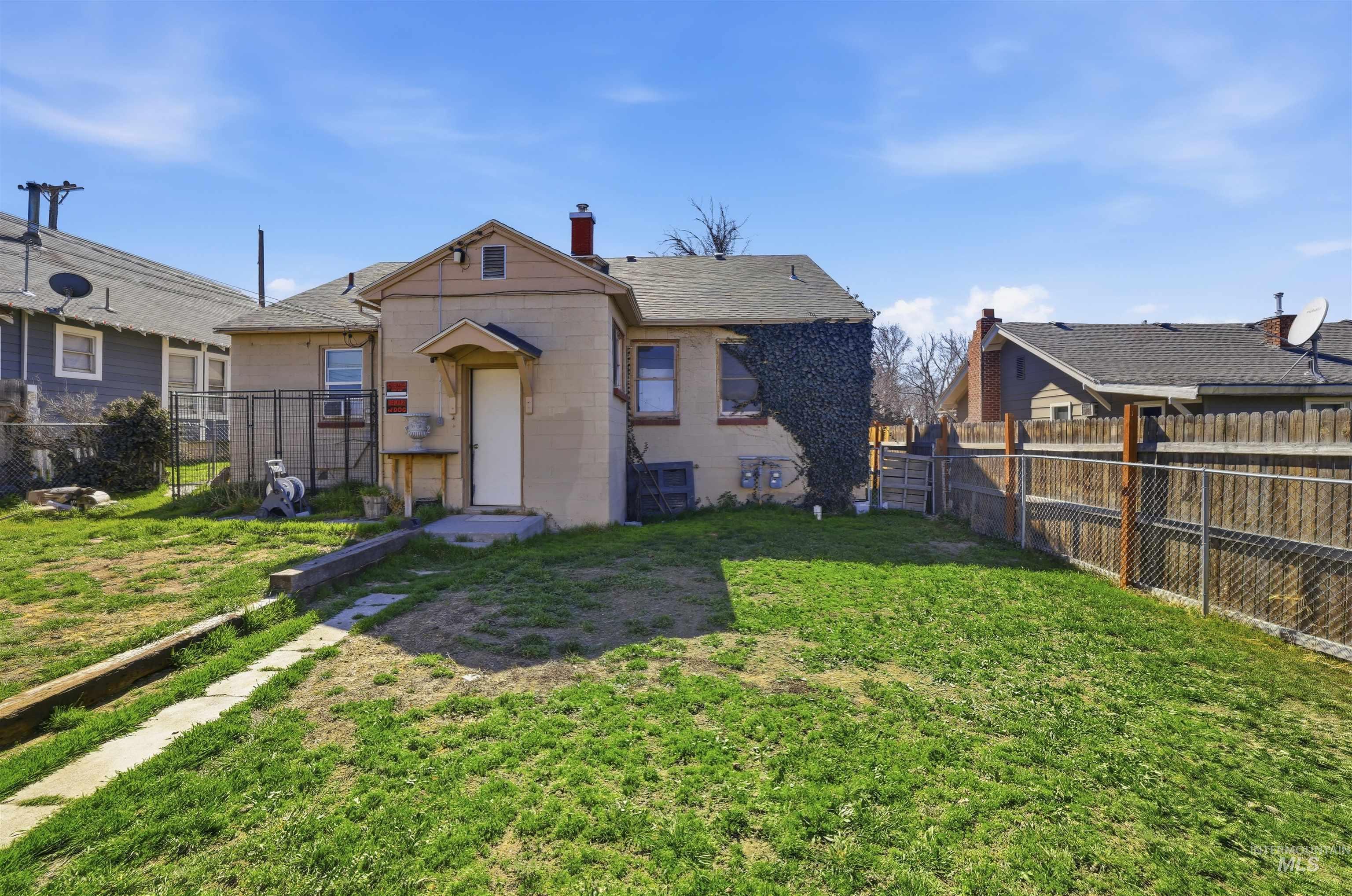 116 13th Avenue North Buhl, ID 83316 - Photo 20 of 37 Back of house with concrete block siding, a fenced backyard, a shingled roof, and a chimney