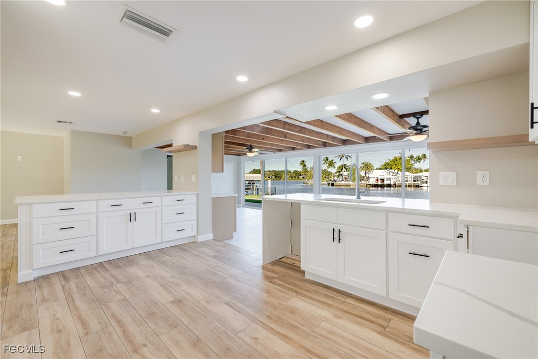 14502 Riverside Drive Fort Myers, FL 33905 - Photo 11 of 33 a kitchen with white cabinets and wooden floors