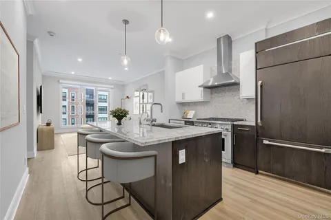 a kitchen with stainless steel appliances granite countertop a sink a stove a refrigerator and island with wooden floor