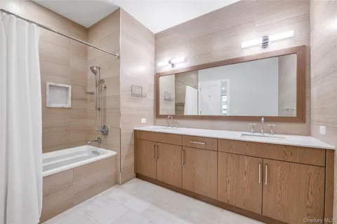 a bathroom with a bathtub a double vanity sink and mirror