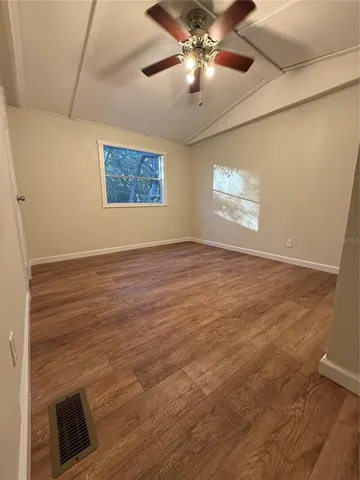 a view of a backyard with a large tree and wooden fence