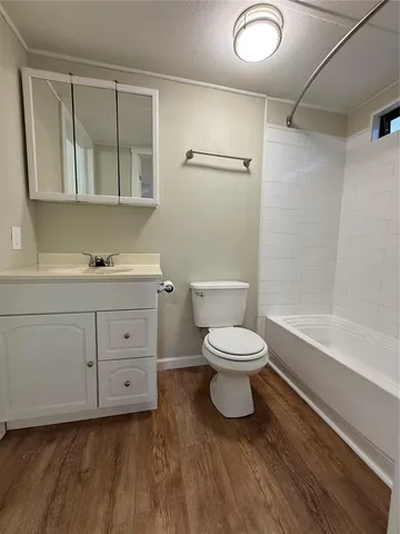 a view of an empty room with wooden floor and a ceiling fan