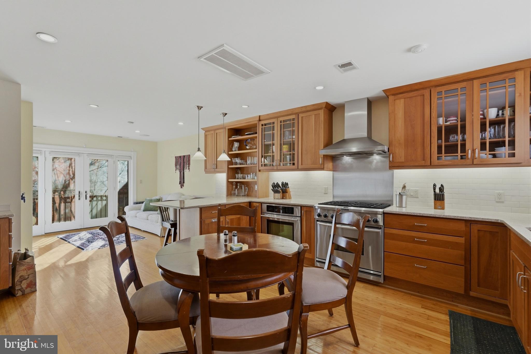 1002 N Street Northwest Washington, DC 20001 - Photo 11 of 33 a kitchen with stainless steel appliances granite countertop a stove top oven a dining table and chairs with wooden floor
