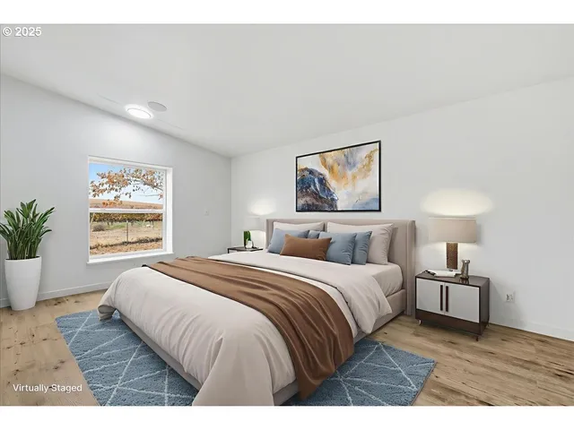 a bedroom with a large bed a painting and a window