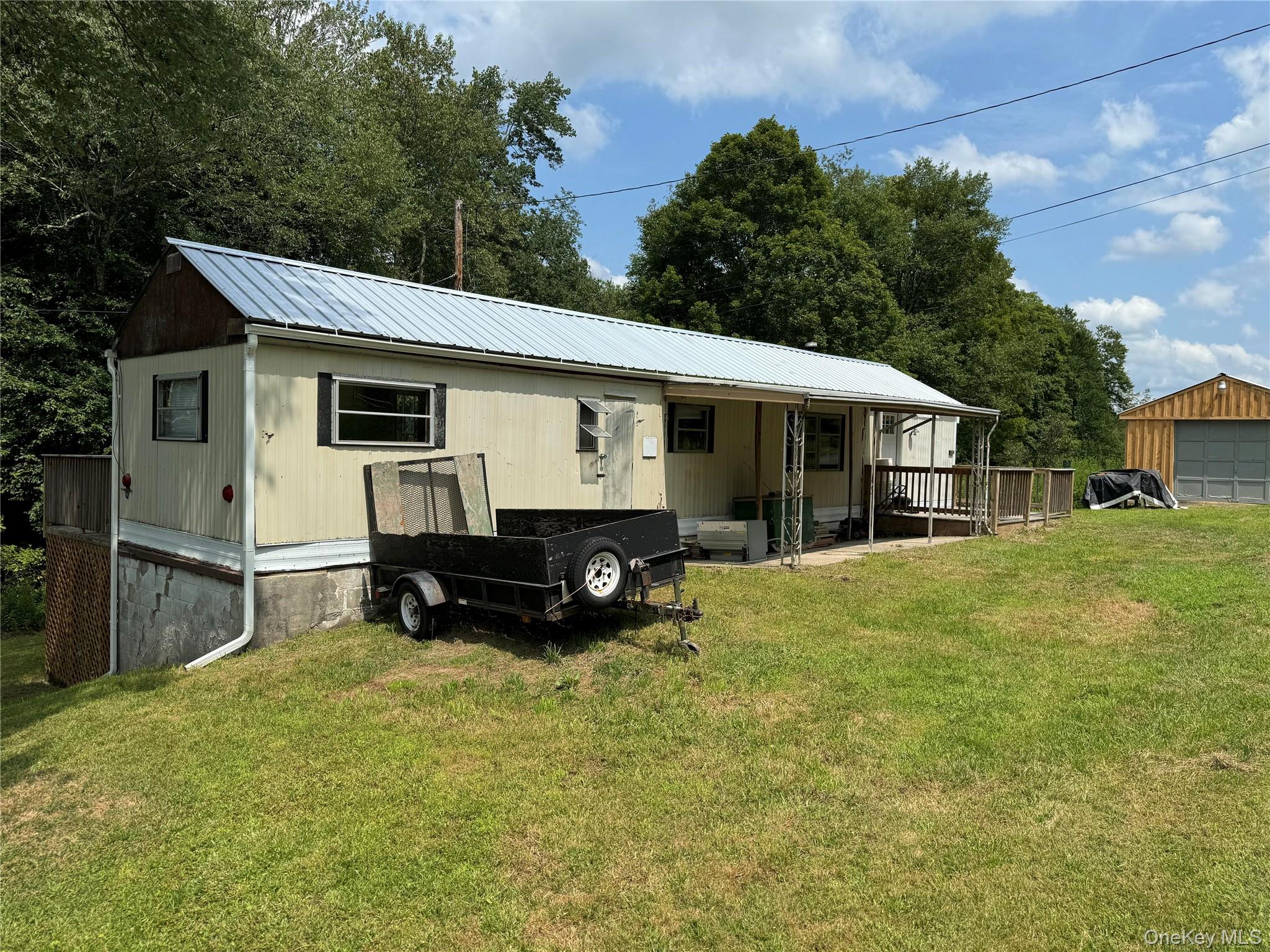 204 Mongaup Road Fallsburg, NY 12747 - Photo 9 of 10 Front view of house featuring a lawn, a metal roof, and a deck