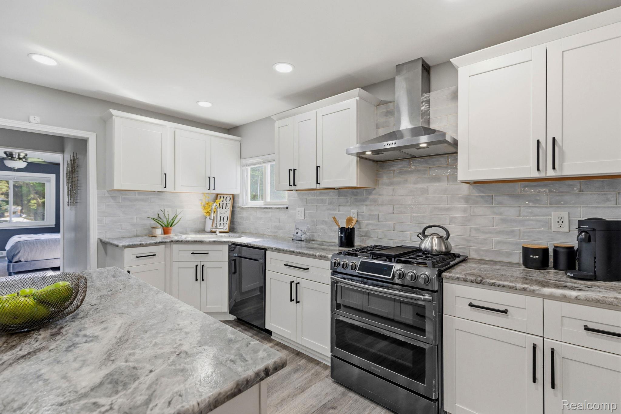 8710 32 Mile Road Washington, MI 48095 - Photo 14 of 60 Kitchen featuring white shaker cabinetry with black hardware, stone countertops, a tile backsplash, stainless steel range with a ventilation hood, and wood-finish flooring