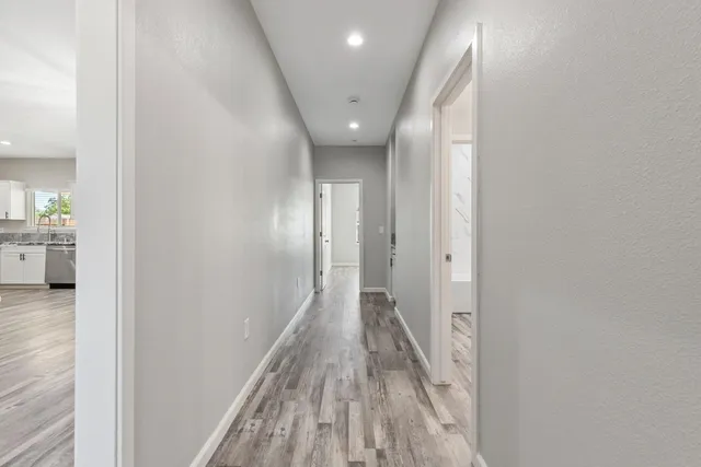 a view of a hallway with wooden floor and a bathroom