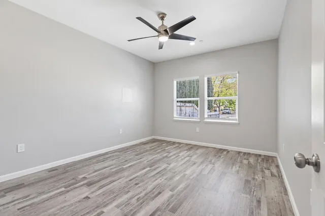 an empty room with wooden floor and windows