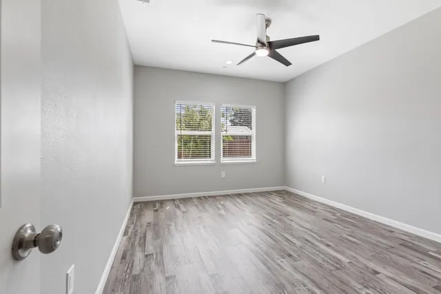 an empty room with windows and fan