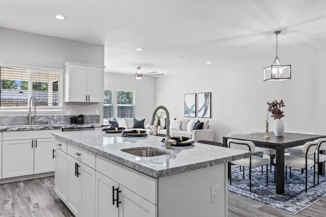a kitchen with a sink a stove and a dining table with wooden floor