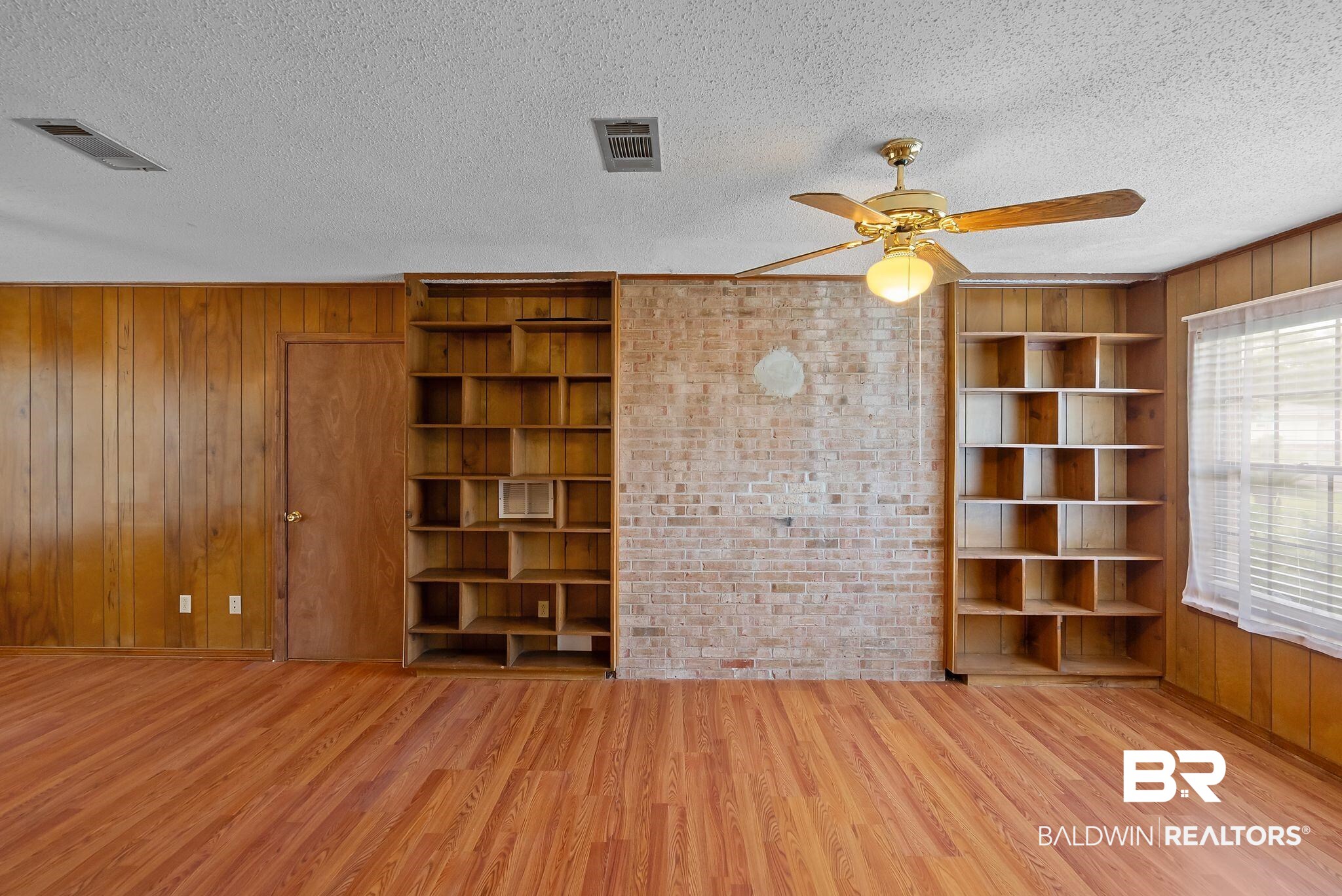 716 North Cedar Street Foley, AL 36535 - Photo 12 of 25 Wood-finish flooring throughout, complemented by wood paneling and a central brick feature wall